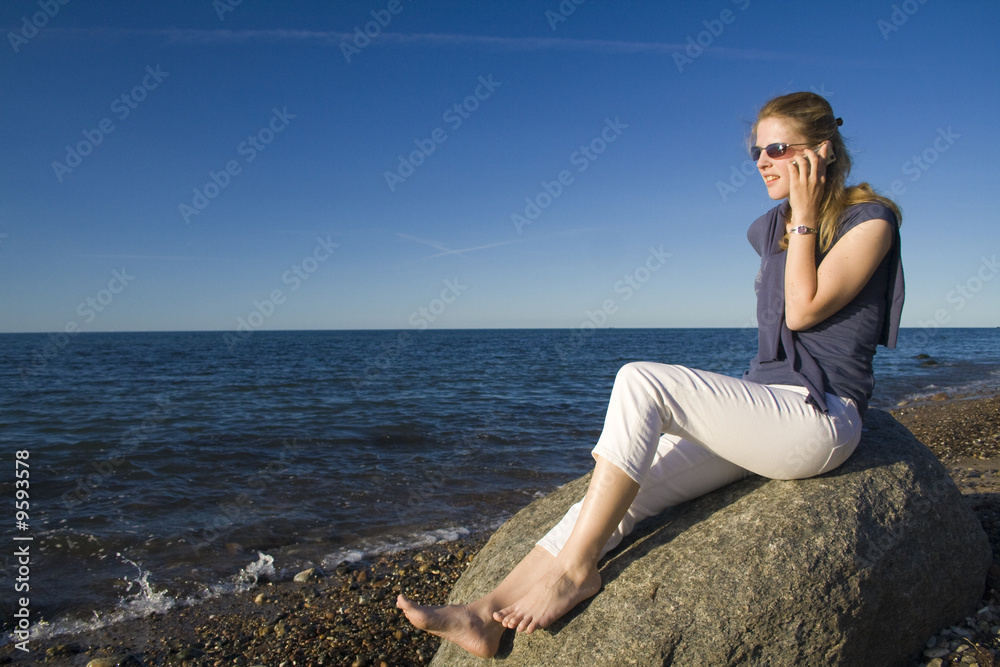 Frau mit Mobiltelefon telefoniert am Strand