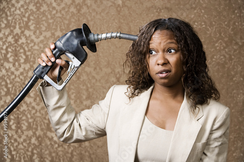 Fotografija Woman holding gas nozzle like a gun to her head