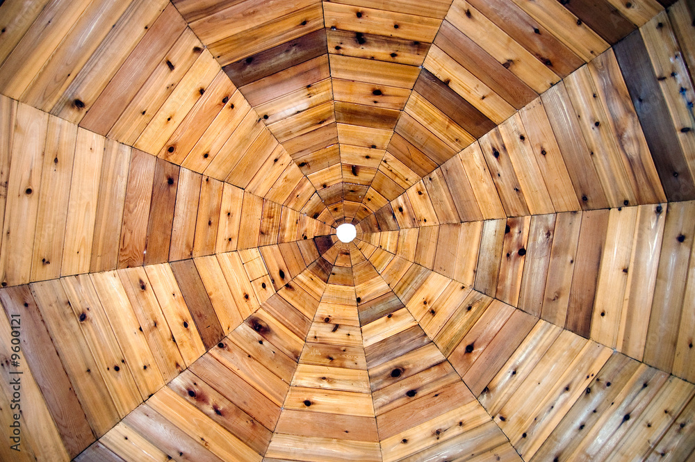 The ceiling of a wooden gazebo resembles a spiderweb pattern