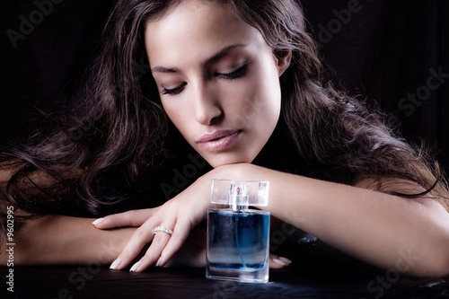 woman with bottle of perfume, studio dark background