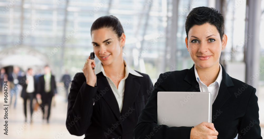 businesswomen at office lobby calling on mobile phone businesswomen at office lobby calling on mobile phone