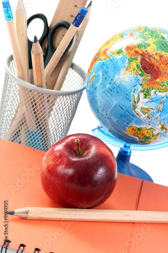 box with pencils spiral netebook and red apple on white photo