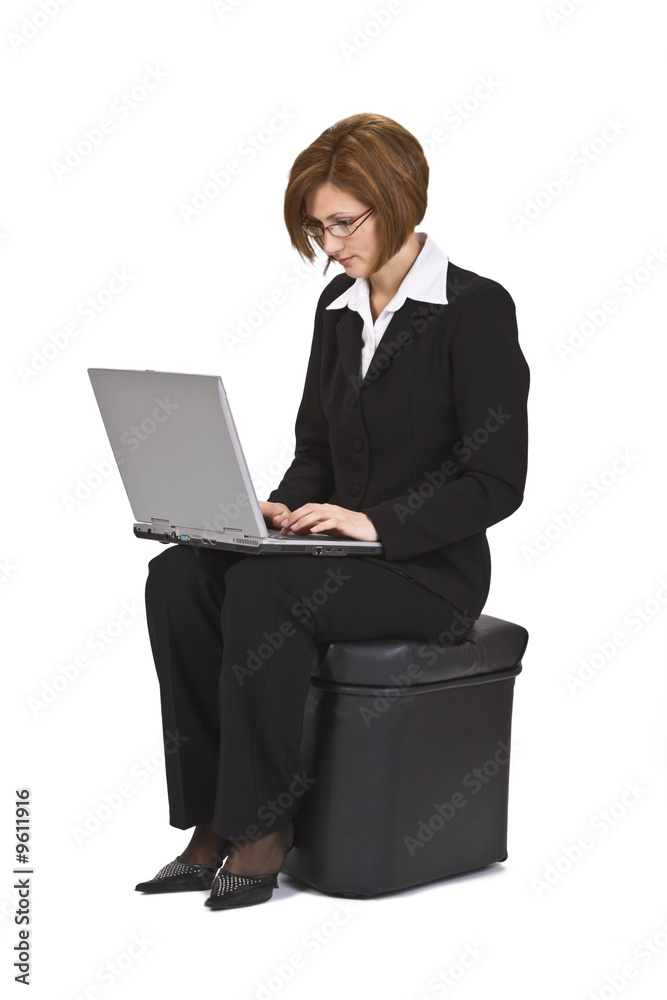 Businesswoman sitting on a pouffe and working on a laptop. Businesswoman sitting on a pouffe and working on a laptop.