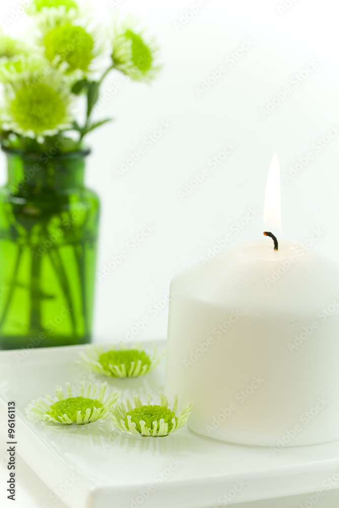 White candle and floating green flowers. Selective focus White candle and floating green flowers. Selective focus