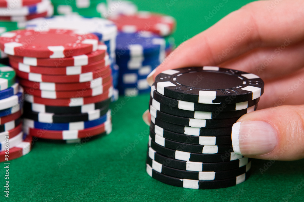 Naklejka premium Female hand putting black poker chips into game.