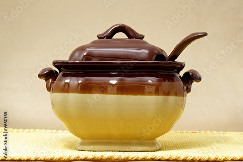 soup tureen on yellow tablecloth, beige background photo