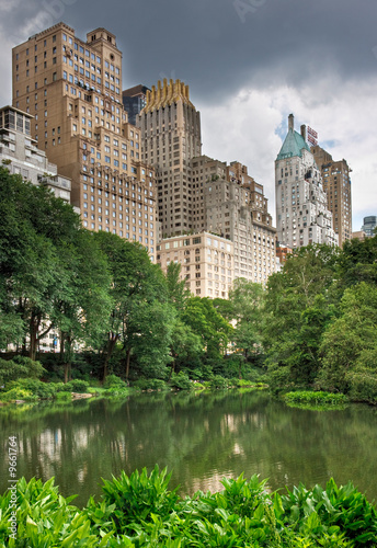 A pond in central park with buildings behind it in New York City