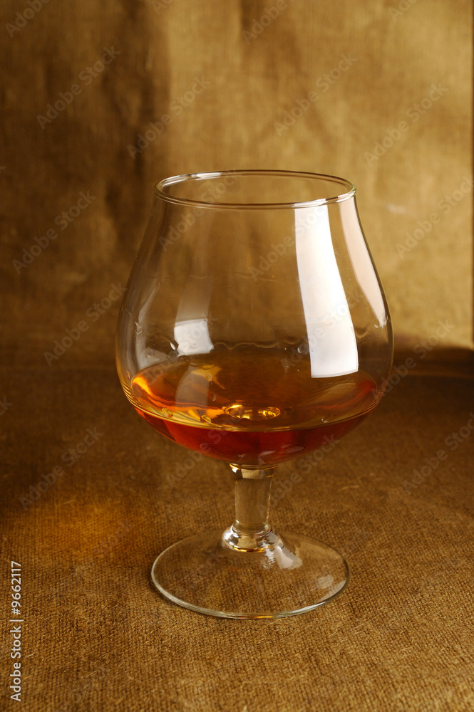 glass of brandy on brown backdrop
