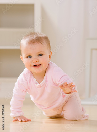 Close up of smiling baby crawling on livingroom floor