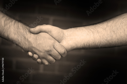 Two business men shaking hand in sepia tone.