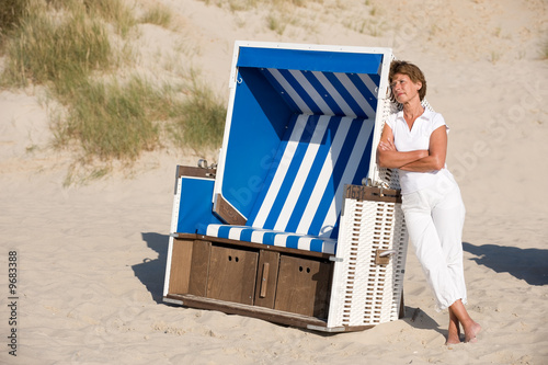 Active senior woman with white clothes at a beachchair.