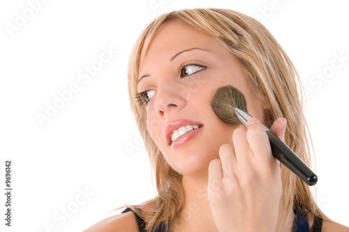 Beautiful young woman puts the fard on her cheeks.