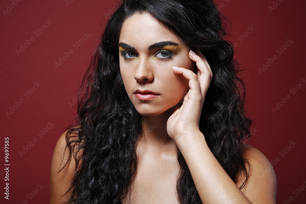 Naklejka premium Dark hair fashion model posing on red background.