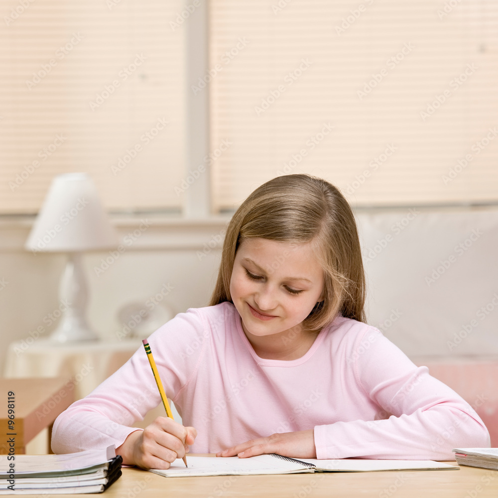 Determined young girl writing homework in notebook Determined young girl writing homework in notebook