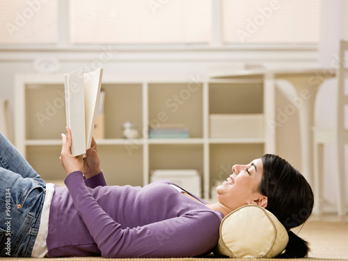 Relaxed woman laying on floor enjoying reading a book