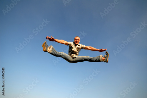 young guy in jump on background dark blue sky, splits