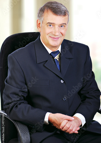 Portrait of middle aged senior business sat in chair smiling