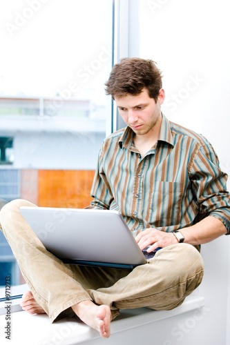 Young casual office worker sitting at office window