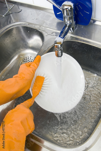 hands in gloves washing dishes at the kitchen