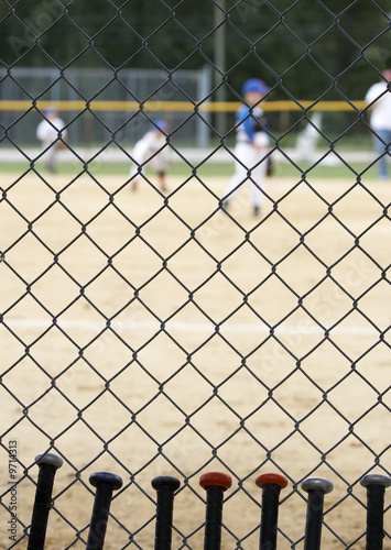 baseball bats learning against dugout fence as game is played
