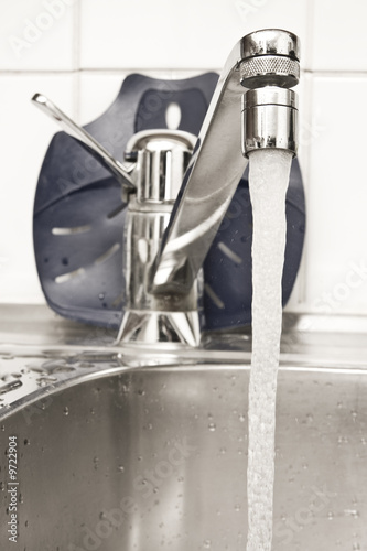 Chrome tap in the kitchen with flowing water photo