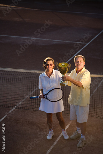 Active senior couple is posing on the tennis court