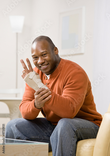 Injured man with wrist splint gesturing the peace symbol
