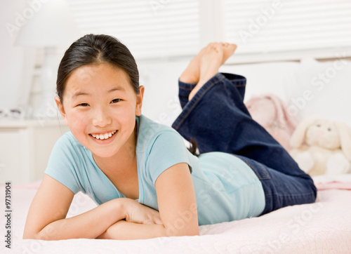фотографія Happy, confident girl laying on bed in bedroom