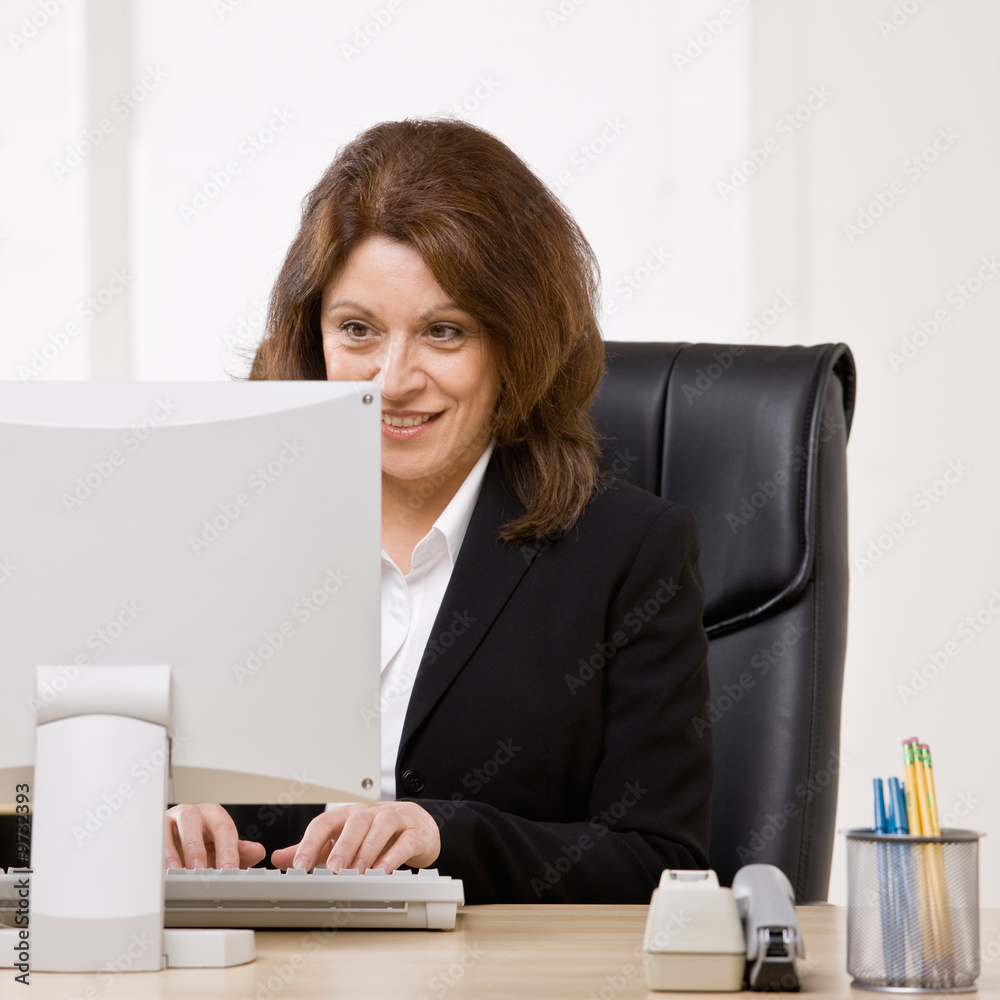 Confident businesswoman typing on computer at desk