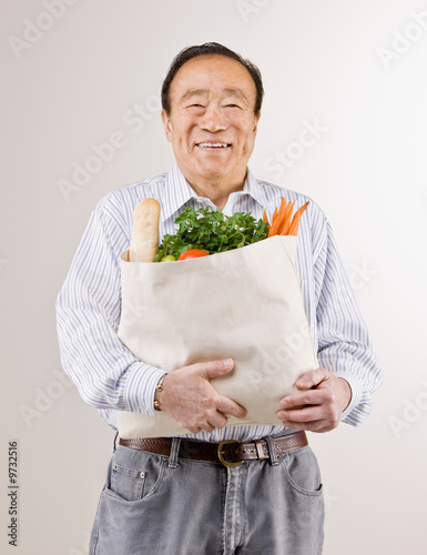 Man holding grocery bag full of fresh fruits and vegetables