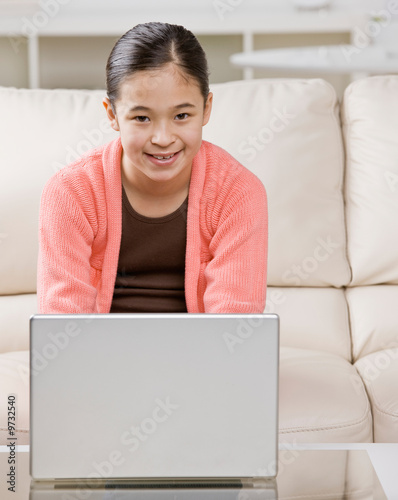 Confident girl typing on laptop in livingroom