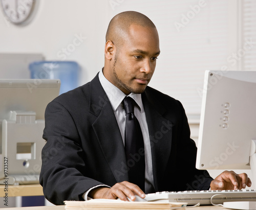 Photos Serious businessman typing on computer at desk