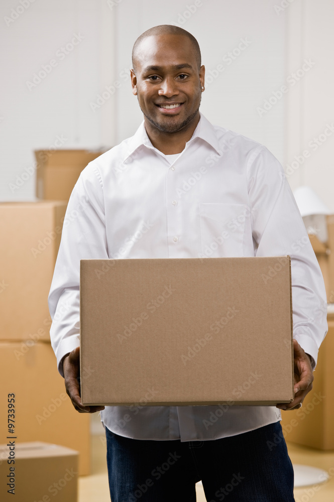 Happy man moving into new home carrying cardboard box Happy man moving into new home carrying cardboard box