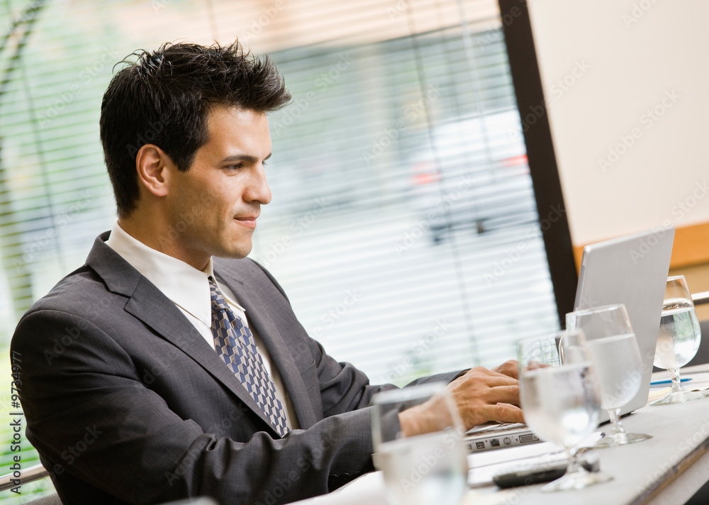 Businessman sitting in conference room working on laptop Businessman sitting in conference room working on laptop