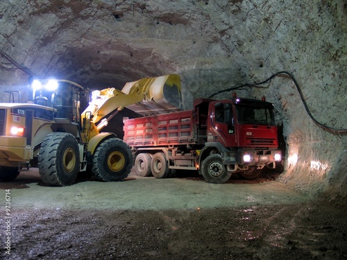 Bulldozer loading a truck in the dark of a mine