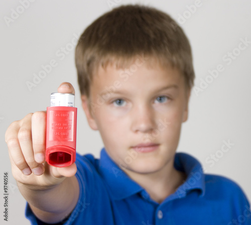 Asthma inhaler being held out by boy in blue shirt