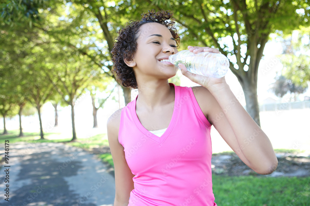 A young pretty african american woman jogger drinking water A young pretty african american woman jogger drinking water