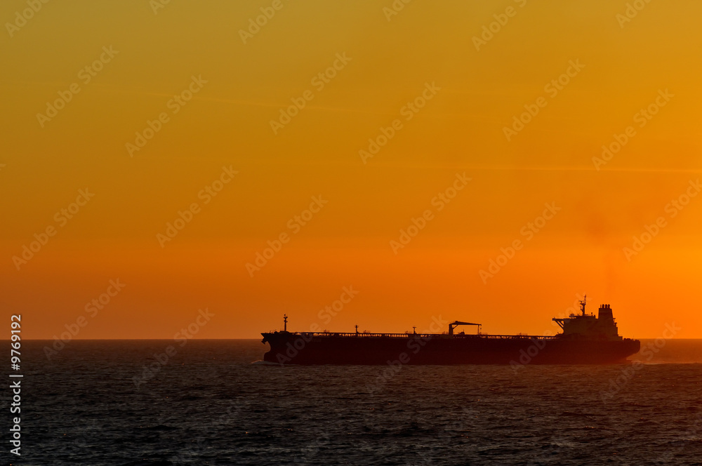 cargo ship by sunset at the ocean