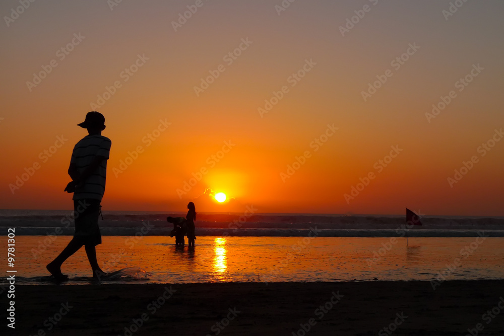 Fototapeta premium A young man walking on the beach at sunset, Kuta Beach, Bali