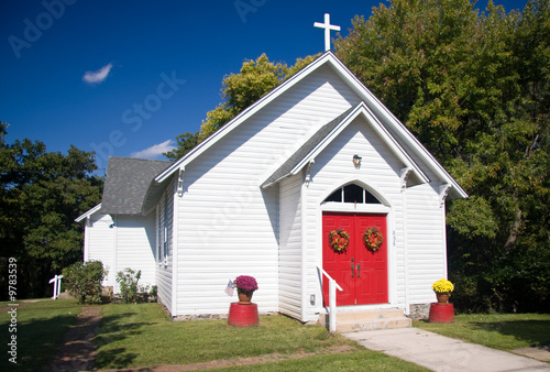 Fototapeta Bright white chapel with red doors decorated with fall flowers