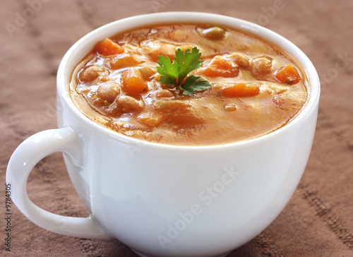 Cup of hearty vegetable soup  on brown cloth.