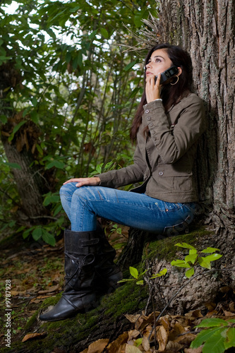 young woman talking by phone on deep forest