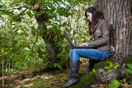 young woman working with laptop on deep forest