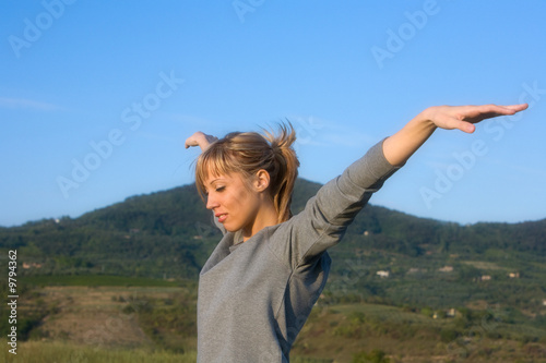 Young smiling woman spreading arms to blue sky