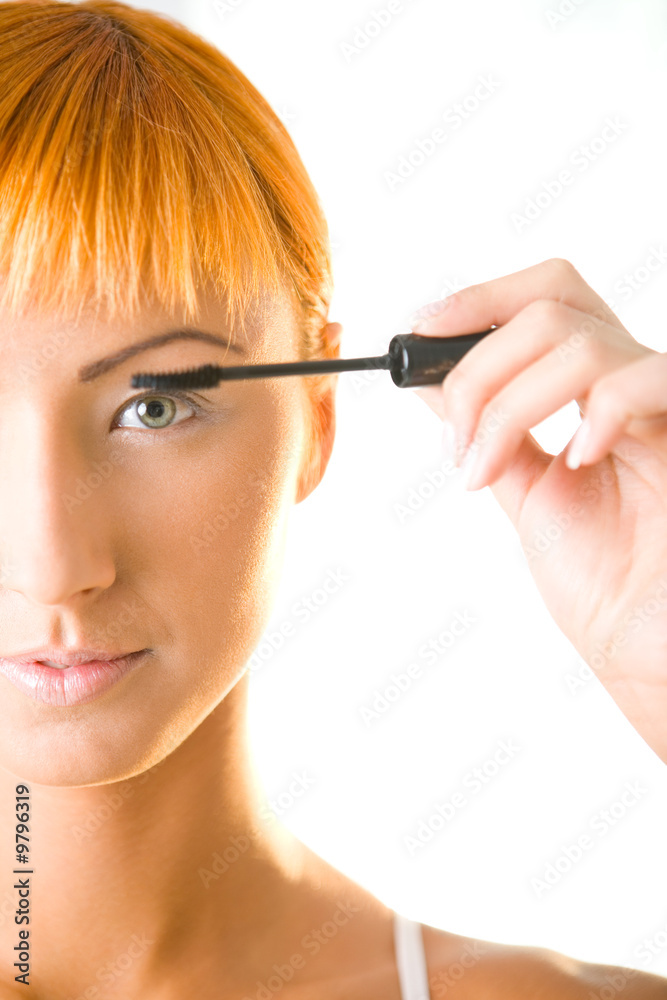 Young woman applying mascara