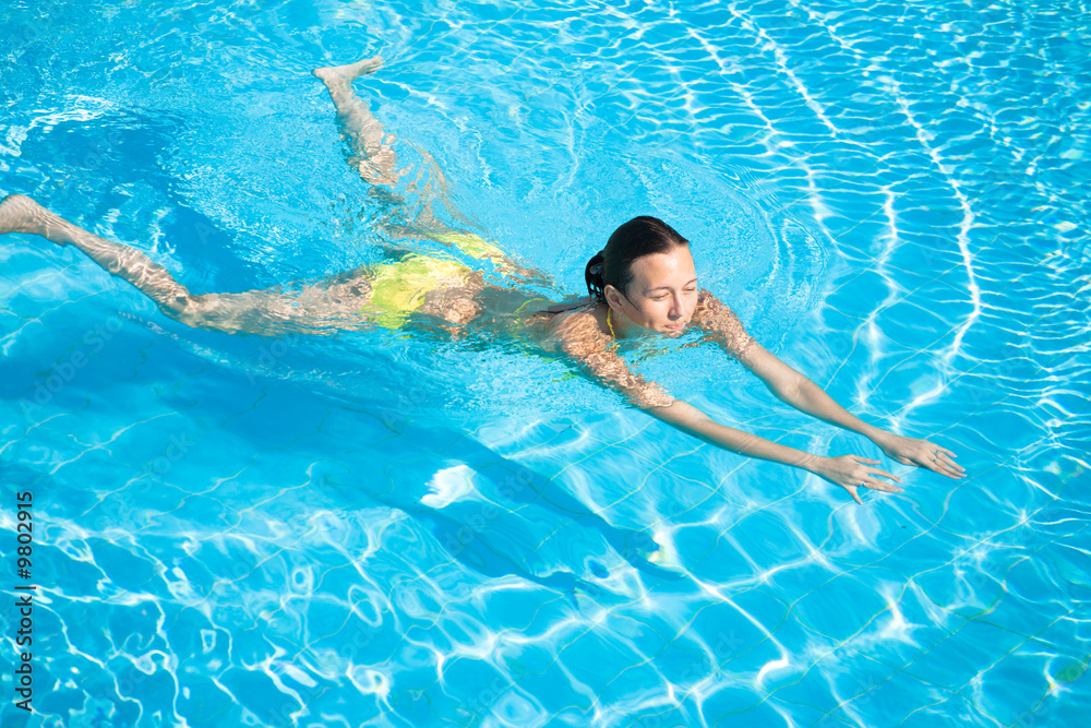 Young beautiful caucasian woman in bikini swimming in pool