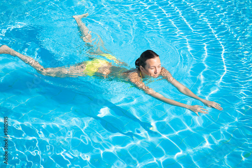 Young beautiful caucasian woman in bikini swimming in pool