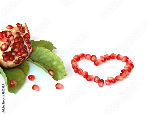 Pomegranate on leaves and heart inscripted from arils photo