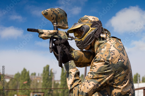 Portrait of a paintball player over blue sky background