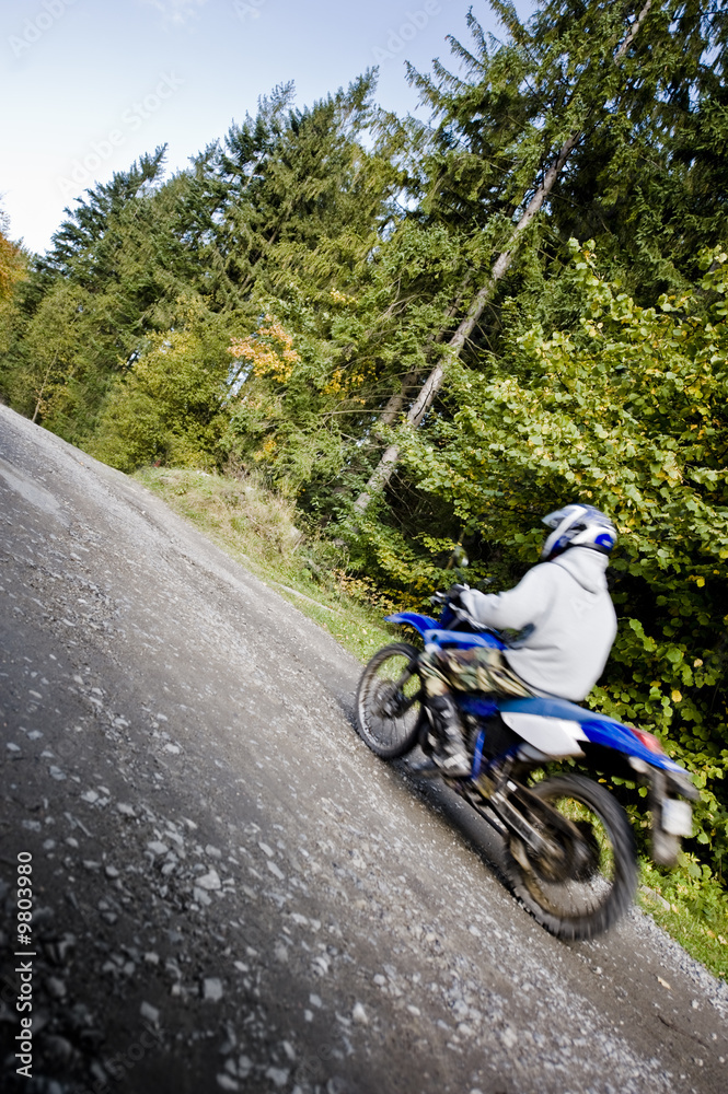 Motion blurred motocross rider, driving fastr through forest Motion blurred motocross rider, driving fastr through forest
